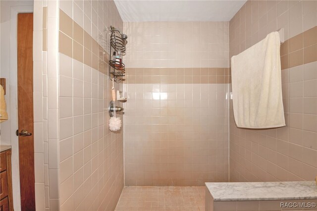 bathroom with a tile shower and vanity