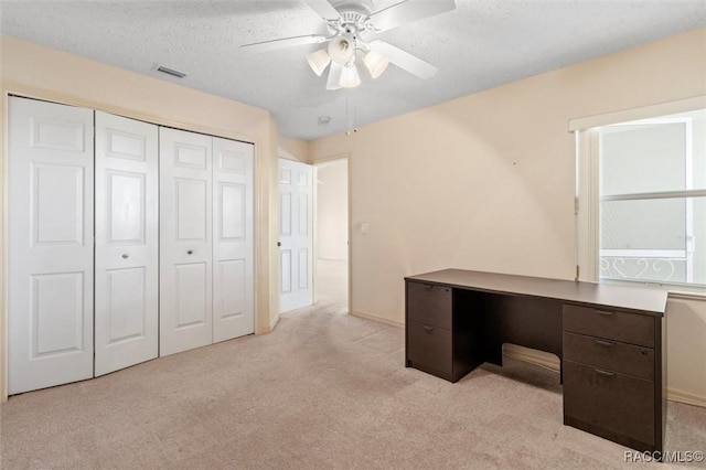 unfurnished office with visible vents, light carpet, a textured ceiling, and a ceiling fan