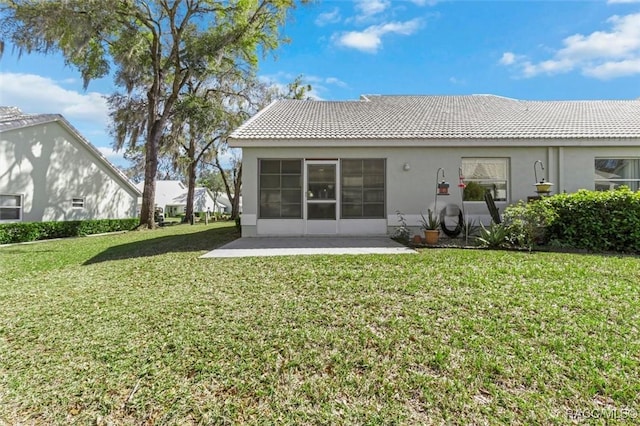 rear view of house with a tiled roof, a yard, a patio area, and stucco siding