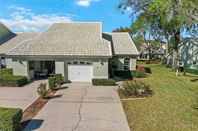 view of front of property with stucco siding, a tiled roof, driveway, and a front lawn