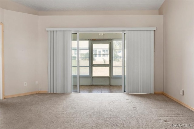 carpeted empty room featuring baseboards