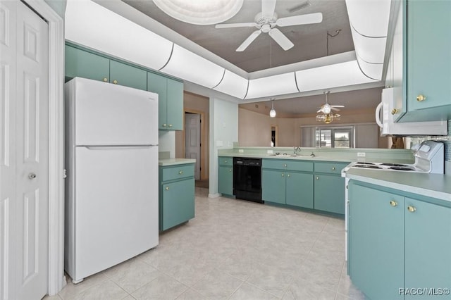 kitchen with white appliances, a tray ceiling, a sink, ceiling fan, and light countertops