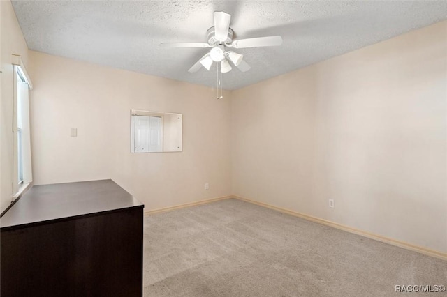 carpeted spare room with baseboards, a textured ceiling, and ceiling fan