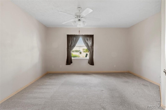 carpeted spare room with a textured ceiling, baseboards, and a ceiling fan