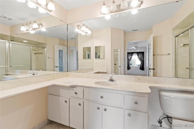 bathroom with double vanity, visible vents, a stall shower, and a sink