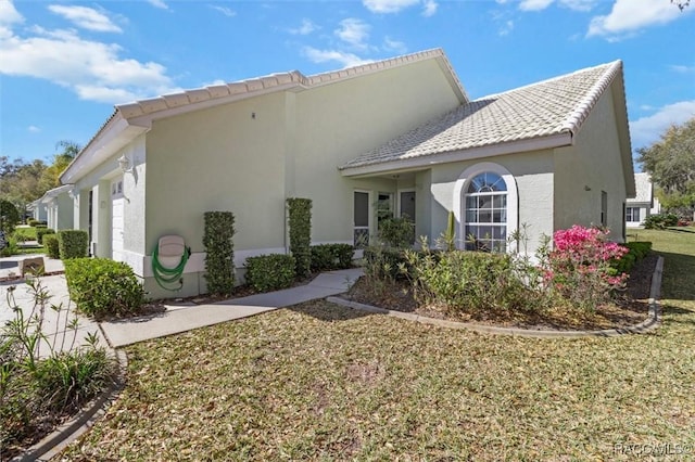 view of property exterior featuring a yard, a garage, and stucco siding