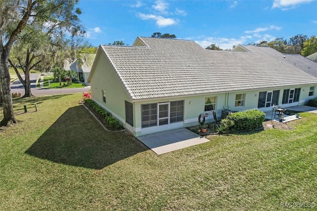 back of property featuring stucco siding, a patio, a yard, and a tiled roof