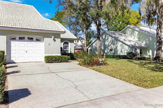 view of side of home with a tile roof, concrete driveway, stucco siding, a yard, and an attached garage