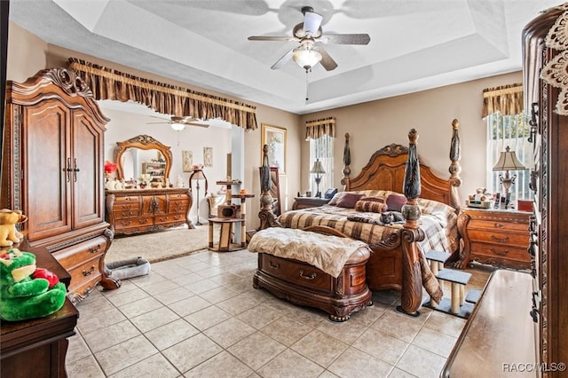 tiled bedroom with a raised ceiling and ceiling fan