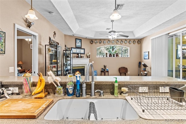 kitchen with a tray ceiling, a textured ceiling, and decorative light fixtures