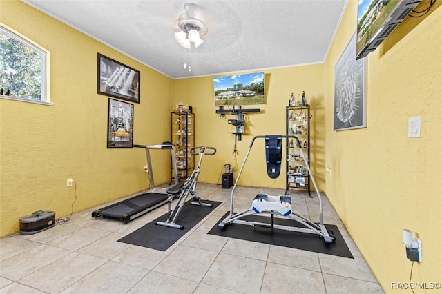 exercise room featuring crown molding, light tile patterned floors, ceiling fan, and a textured ceiling