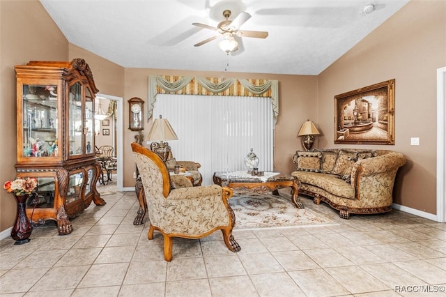 living area featuring ceiling fan, light tile patterned floors, and vaulted ceiling