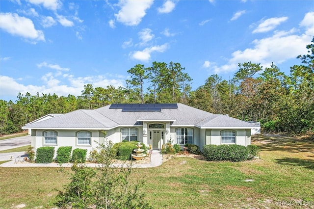 single story home with a front yard and solar panels