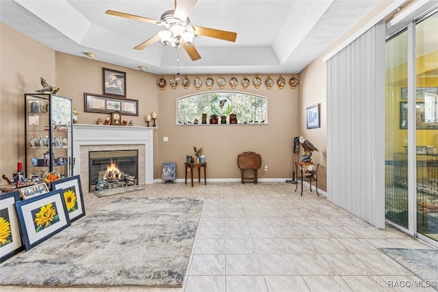 sitting room with a raised ceiling, a tile fireplace, ceiling fan, and tile patterned flooring