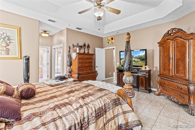 bedroom with ceiling fan, a raised ceiling, light tile patterned floors, and ensuite bath