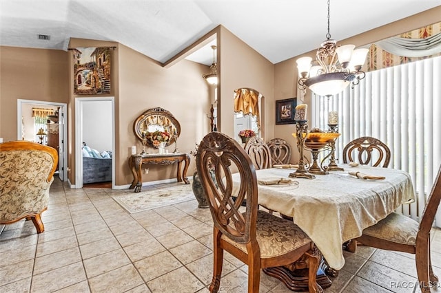 dining area with tile patterned flooring, an inviting chandelier, and lofted ceiling