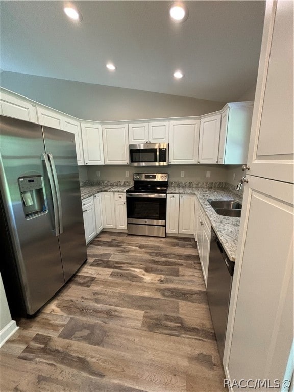 kitchen featuring sink, white cabinetry, stainless steel appliances, and vaulted ceiling