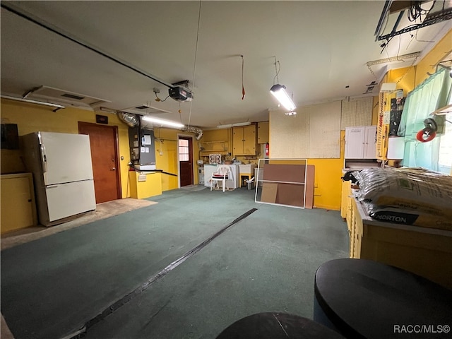 garage with heating unit, a garage door opener, and white refrigerator