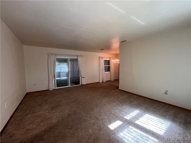 carpeted spare room with a chandelier