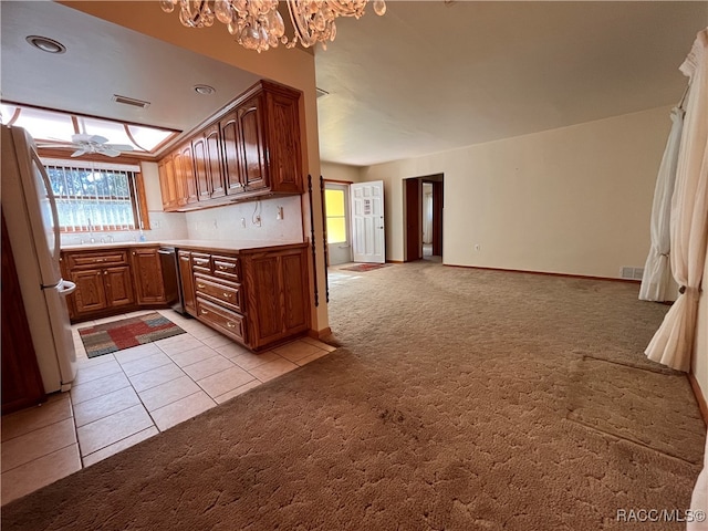 kitchen featuring white fridge, light colored carpet, and ceiling fan with notable chandelier