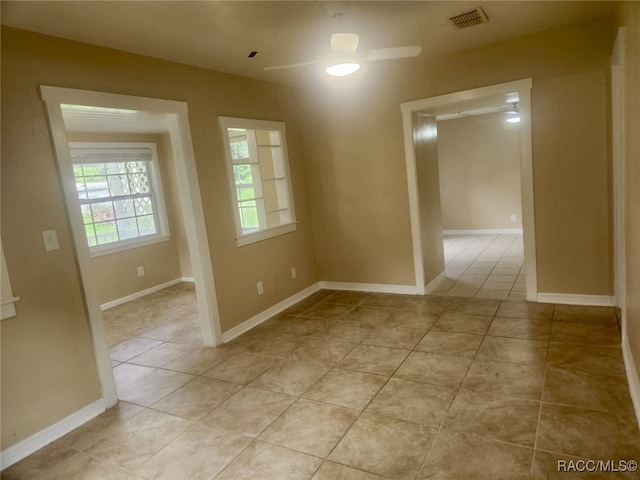 empty room with ceiling fan and light tile patterned flooring