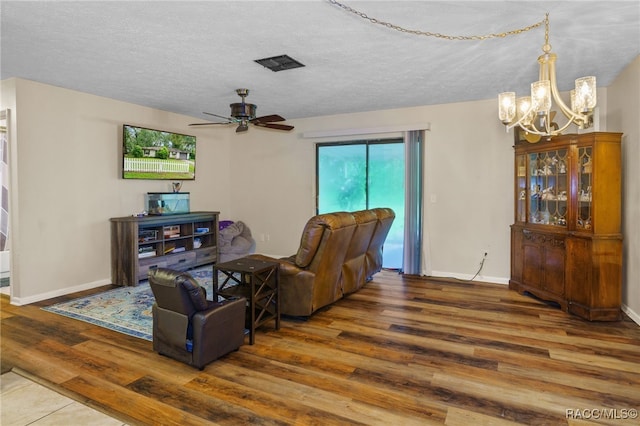 living room featuring ceiling fan with notable chandelier, a textured ceiling, and hardwood / wood-style flooring