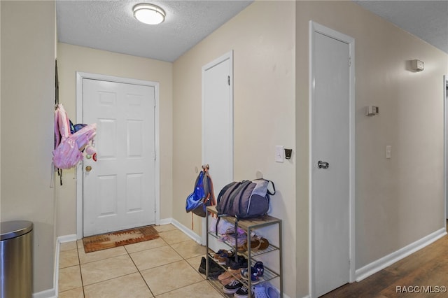 entryway with light tile patterned floors and a textured ceiling