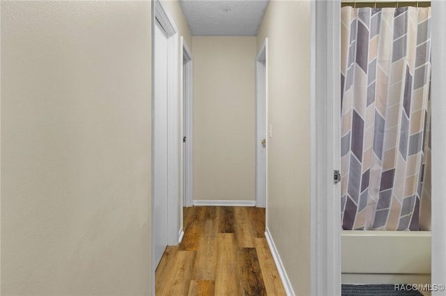 hall with a textured ceiling and hardwood / wood-style flooring