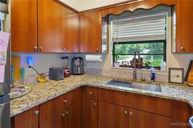 kitchen featuring light stone counters and sink