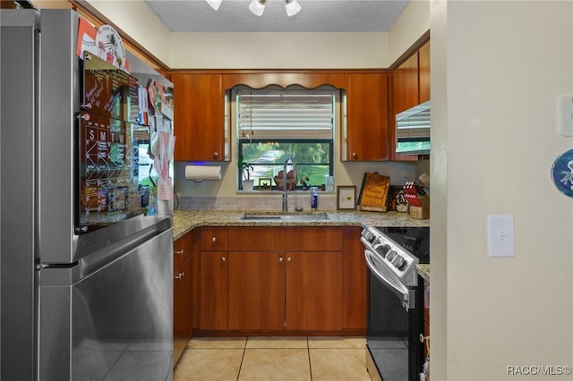 kitchen with light stone counters, sink, a textured ceiling, and appliances with stainless steel finishes