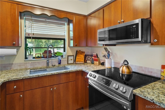 kitchen with light stone countertops, appliances with stainless steel finishes, tile patterned floors, and sink