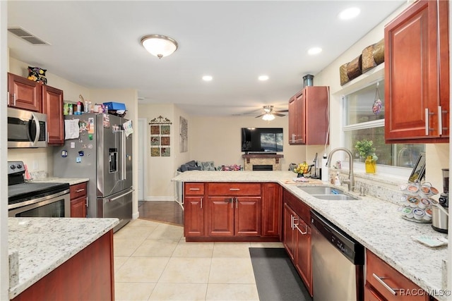 kitchen with sink, light tile patterned floors, appliances with stainless steel finishes, light stone countertops, and kitchen peninsula