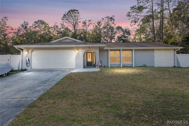 ranch-style home featuring a garage and a yard