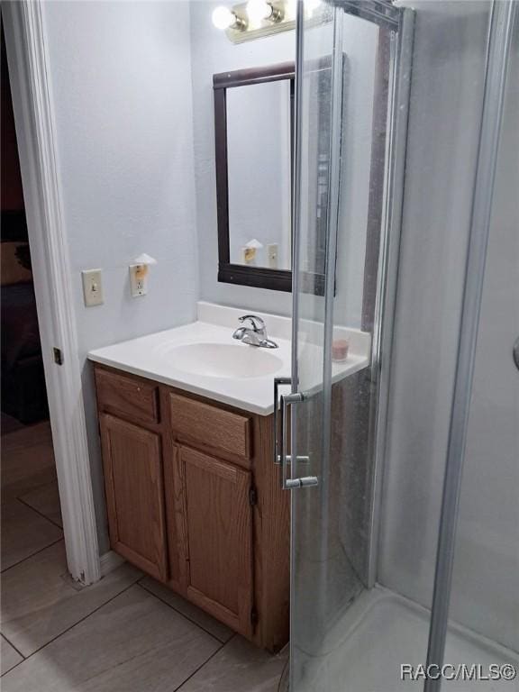 bathroom with tile patterned flooring, vanity, and walk in shower