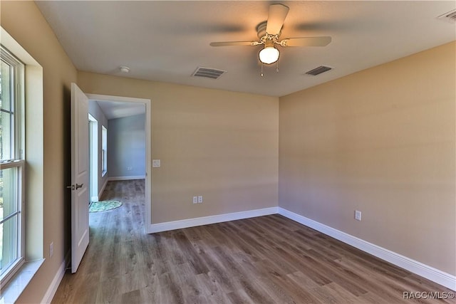 spare room featuring visible vents, baseboards, and wood finished floors