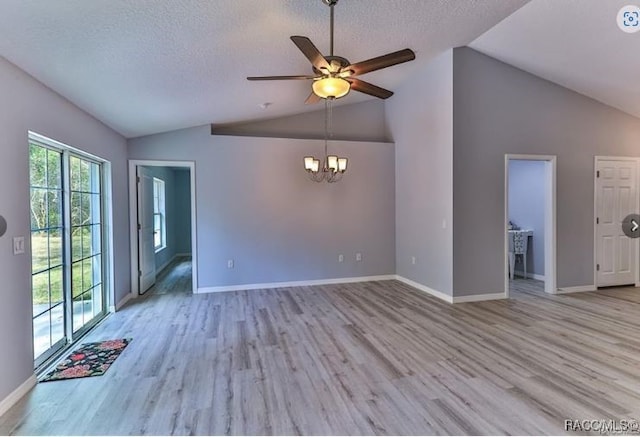 unfurnished living room with a textured ceiling, ceiling fan with notable chandelier, light hardwood / wood-style flooring, and lofted ceiling