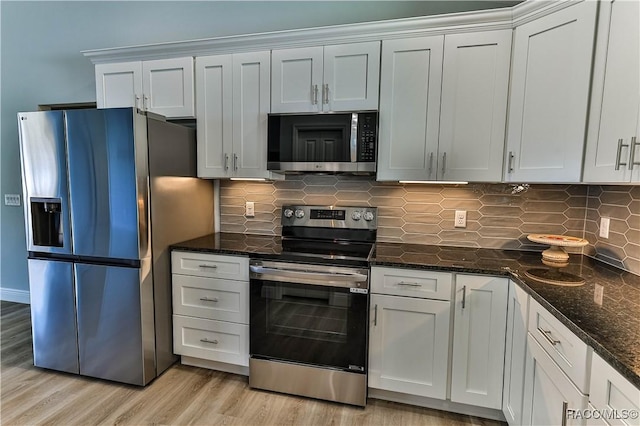 kitchen featuring dark stone countertops, stainless steel appliances, tasteful backsplash, and light wood-style flooring