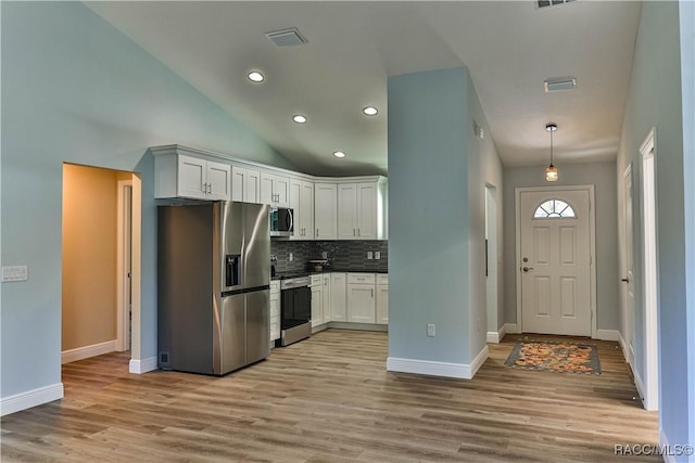 kitchen featuring visible vents, stainless steel appliances, white cabinets, light wood-type flooring, and backsplash