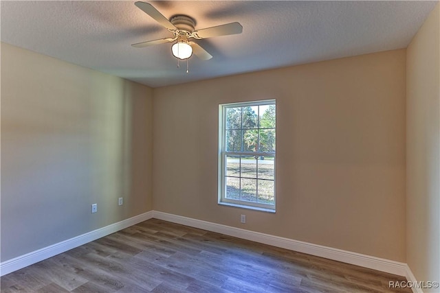 empty room featuring ceiling fan, wood finished floors, baseboards, and a textured ceiling