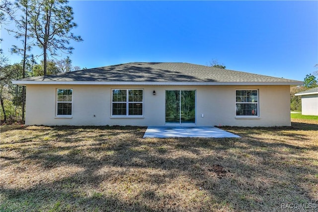 back of property featuring a lawn, a patio, and roof with shingles