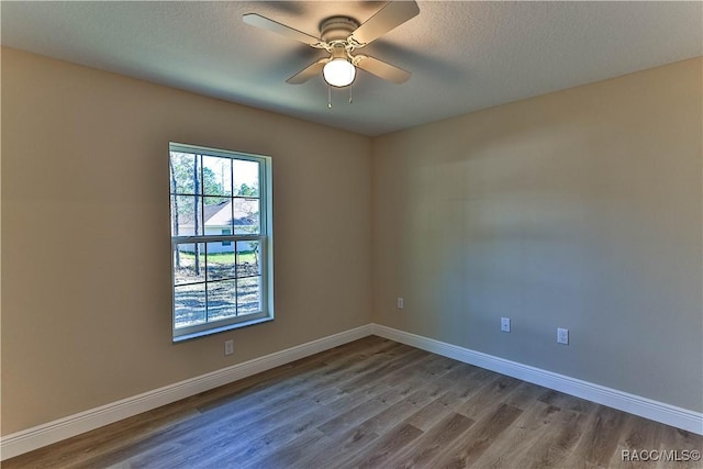 unfurnished room with a ceiling fan, wood finished floors, and baseboards