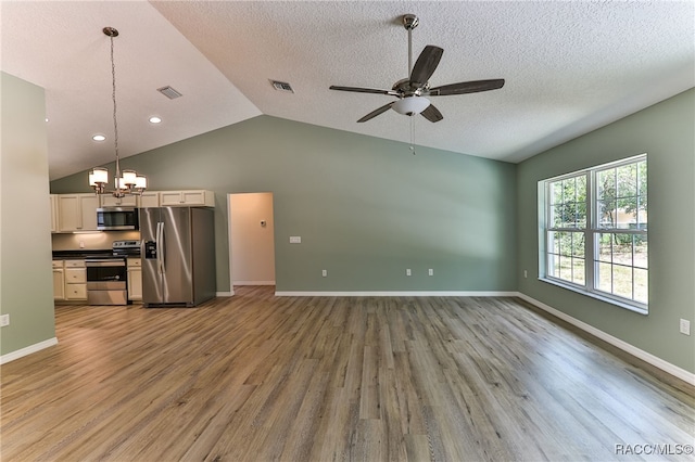 unfurnished living room featuring a textured ceiling, hardwood / wood-style floors, ceiling fan with notable chandelier, and lofted ceiling