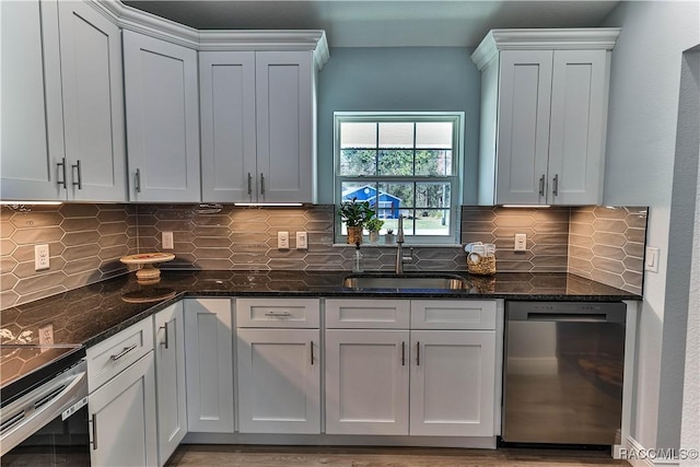 kitchen with dishwasher, dark stone countertops, tasteful backsplash, and a sink