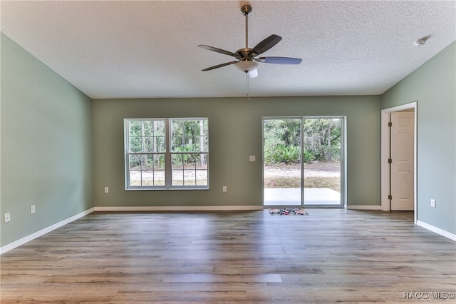 spare room with ceiling fan, a healthy amount of sunlight, a textured ceiling, and light wood-type flooring