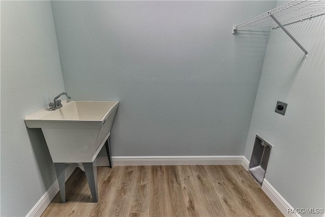 clothes washing area with electric dryer hookup, baseboards, laundry area, and light wood finished floors