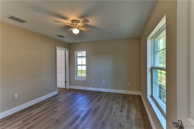 spare room featuring visible vents, plenty of natural light, and dark wood finished floors