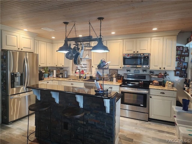 kitchen featuring sink, a kitchen breakfast bar, light hardwood / wood-style floors, decorative light fixtures, and appliances with stainless steel finishes