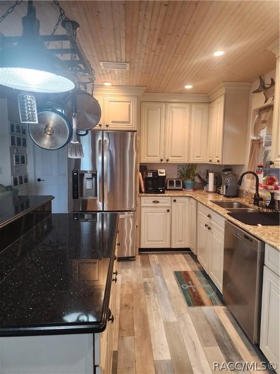 kitchen with appliances with stainless steel finishes, light stone counters, sink, light hardwood / wood-style flooring, and white cabinetry