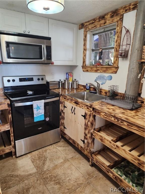 kitchen featuring white cabinets, a textured ceiling, stainless steel appliances, and sink