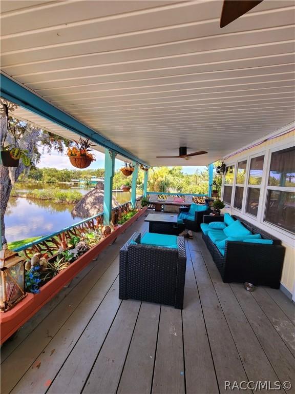 wooden terrace featuring outdoor lounge area, ceiling fan, and a water view